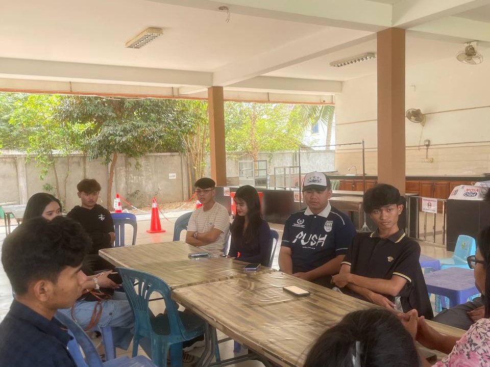 GTIS graduates sitting around tables in the covered area, talking together