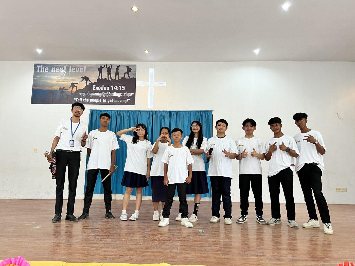 Music Club students on the hall stage, one holding a microphone and another a pair of drumsticks
