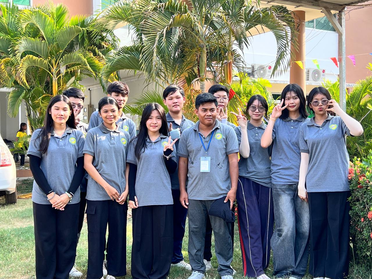 GTIS student leaders in grey school polo shirts standing together outside among the palm trees