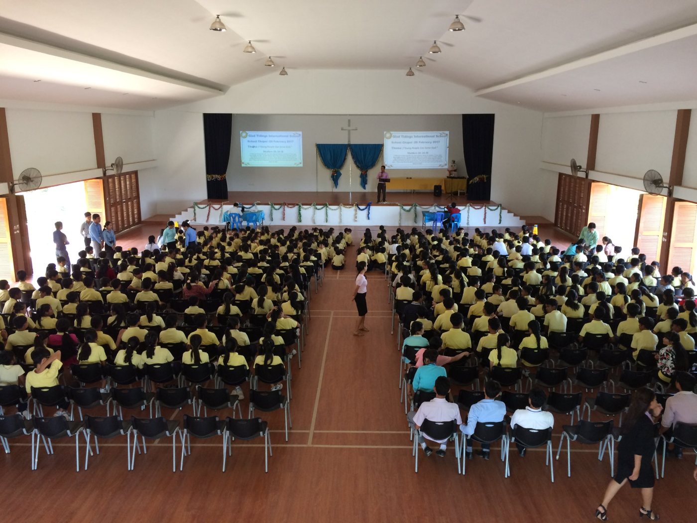 The whole school seated in the hall for chapel, facing a cross on the platform